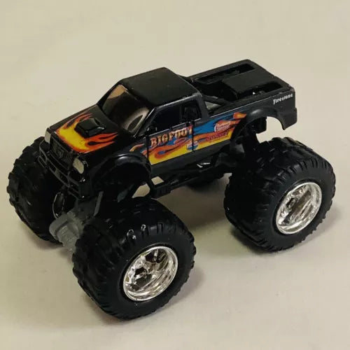 Black diecast monster truck with oversized tires, flame graphics on hood and side