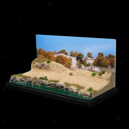 Mini desert diorama model with sandy dunes and sparse trees on a green base