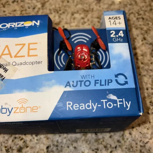 Mini red quadcopter drone with propellers, shown on Horizon Hobby retail box