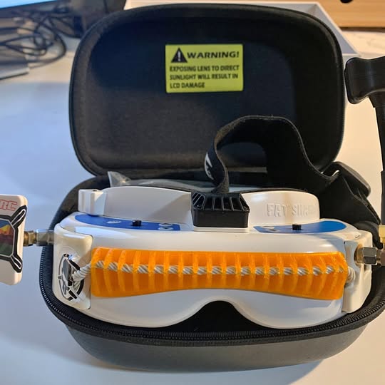 White and orange drone with open black protective case and orange front bumper