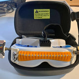 White and orange drone with open black protective case and orange front bumper