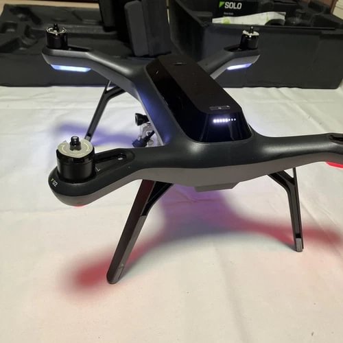 Quadcopter drone with GPS, four propeller arms and landing legs, dark gray body