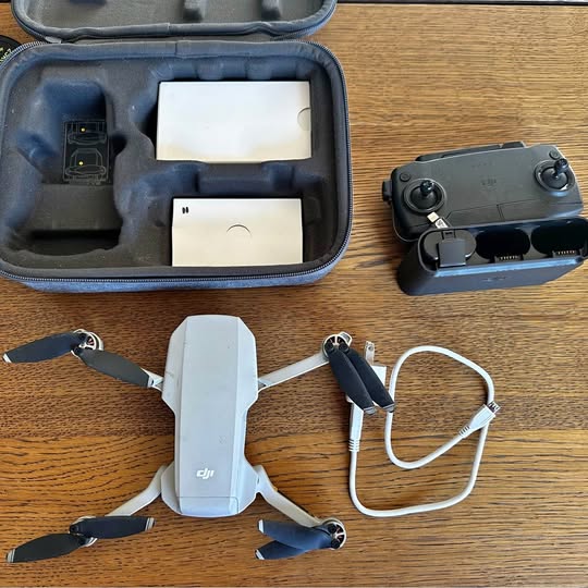 Foldable quadcopter drone with four propellers and charging cables in a zip case