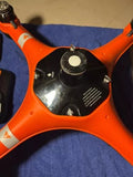 Orange quadcopter drone top view with central camera and control panel markings