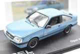 Light blue diecast coupe car model with black wheels, displayed on a branded base