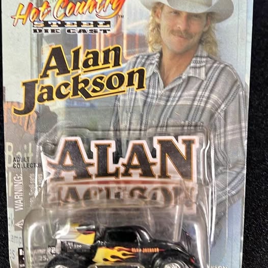 Diecast collectible car in clear blister pack, black and yellow flame graphics.