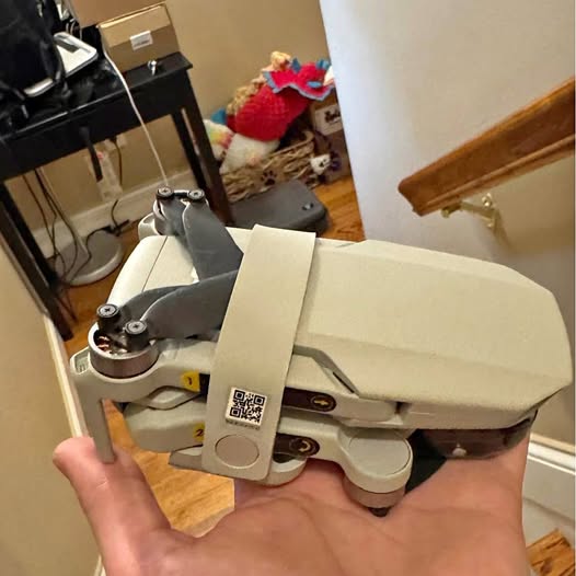DJI Mini 3 drone, gray body with propellers, held in hand