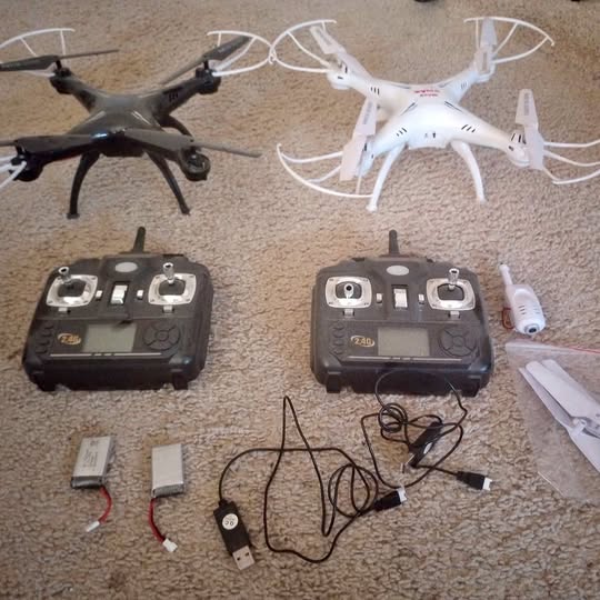 Drone set with two quadcopter drones, two controllers, and charging cables