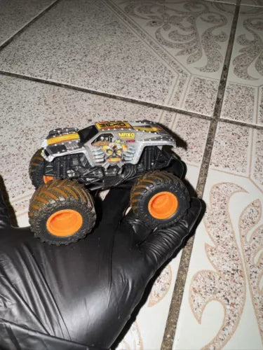 Diecast monster truck with dirt on tires, detailed black and orange wheels