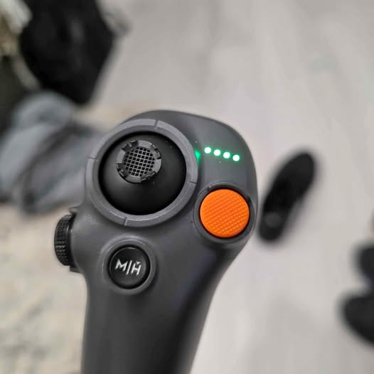 DJI Motion Controller 3 with orange action button and mic grille, green status LEDs