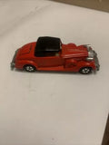 Red diecast roadster toy car with black convertible top and detailed chrome bumpers