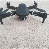 Foldable black quadcopter drone with front camera and four propellers