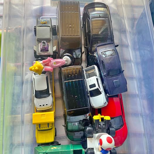 Assorted diecast vehicles in clear display box, including trucks and cars.