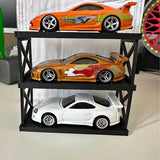 Diecast car display stand with three model cars: orange, gold, and white