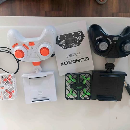Drone controller set with white remote and black remote components, plus drone parts