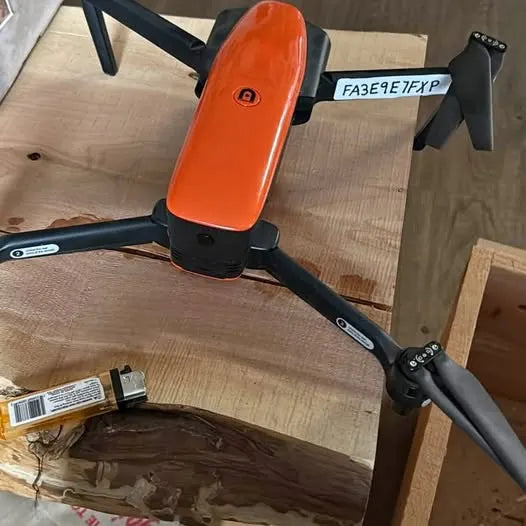 Orange quadcopter drone with black prop guards and landing legs
