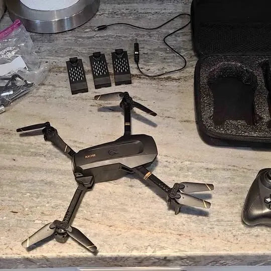 Foldable quadcopter drone with four propellers, accessories and batteries nearby