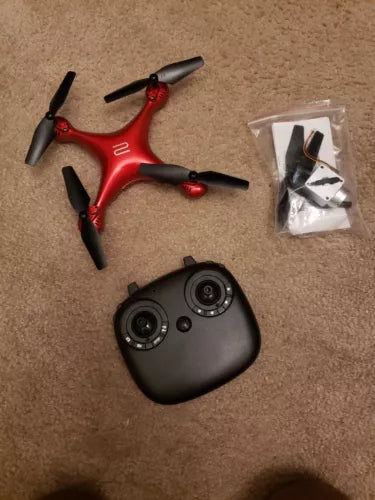 Red and black quadcopter drone with four propellers and black remote controller