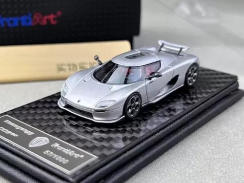 Silver sports racing diecast car model with front three-quarter view on base