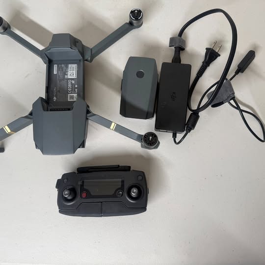 Foldable quadcopter drone with remote controller, batteries, and cables in view