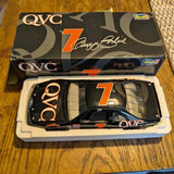 Diecast race car model in open box, black with gold accents and number 7