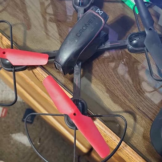 Red and black quadcopter drone with camera body and propellers
