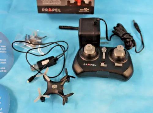 Black micro quadcopter drone with controller, propellers, and charging accessories