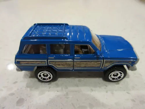 Blue diecast toy SUV, side view with black wheels and silver grille