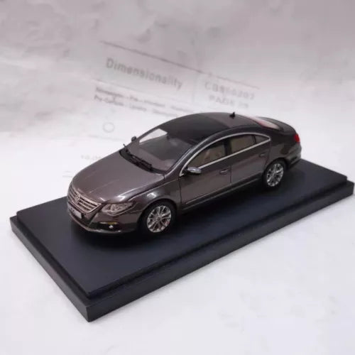 Diecast dark sedan model on display base, front 3/4 view.