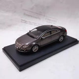 Diecast dark sedan model on display base, front 3/4 view.