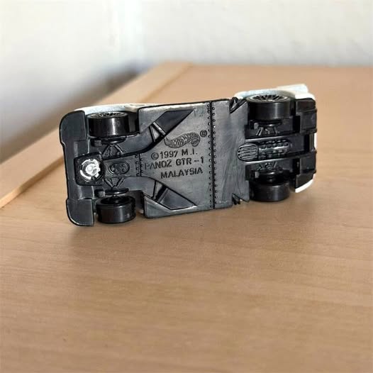 Black and gray diecast race car with cockpit detail, rear wheels visible