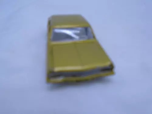 Vintage diecast toy car with gold body and clear windshield, front view