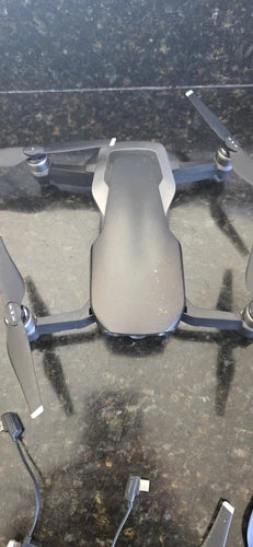 Compact quadcopter drone with gray body, front sensors, and four propellers