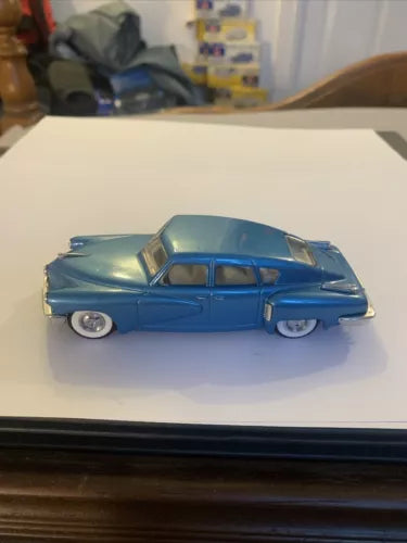 Blue vintage diecast sedan model car with chrome trim and whitewall wheels