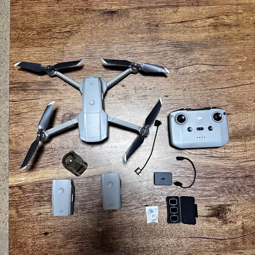 Grey quadcopter drone with propellers, controller, batteries, and charging cables