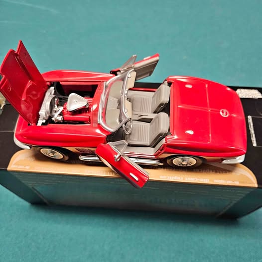 Red diecast car with doors open and detailed interior on display base