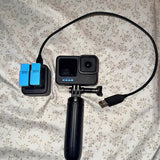 GoPro action camera in waterproof case with handle mount and USB cable