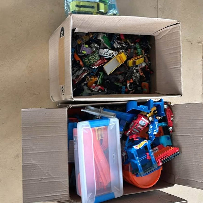 Diecast toy vehicle assortment in open cardboard boxes, mixed colors and parts
