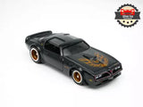 Black 1:64 diecast muscle car model with flame decal and gold wheels, front 3/4 view
