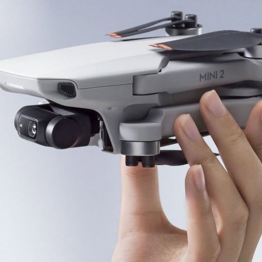 DJI Mini 2 SE drone with front camera and propellers, held in hand