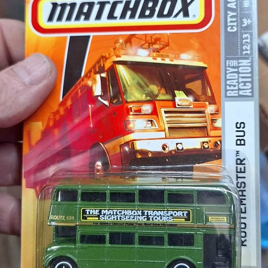 Green die-cast tour bus with open windows on retail blister packaging