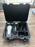 Hard travel case open with white drone and camera module, plus controller accessories