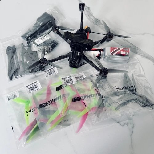 FPV drone kit with black quadcopter frame, propellers, and spare parts