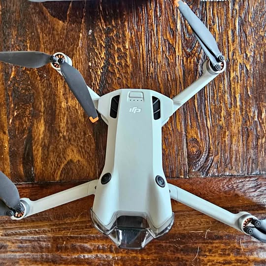 DJI Mini 4 Pro drone with four gray propellers, front camera and landing legs