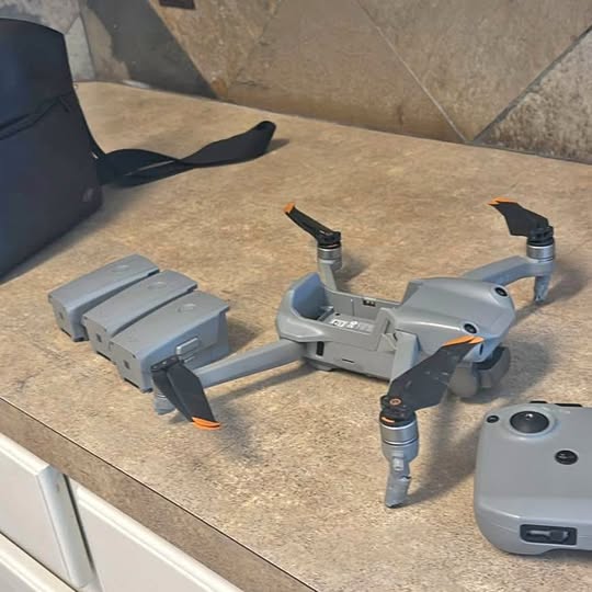 Gray quadcopter drone with four propellers and a handheld controller