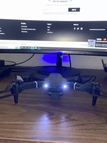 Small black quadcopter drone with blue lights and central camera mount
