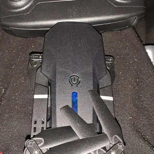 Black drone body with blue power indicator and folding arms