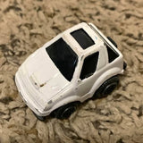 Small white diecast toy car with black windows, front-side view