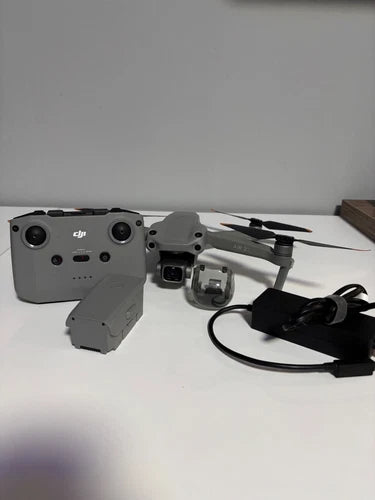 Grey quadcopter drone with remote controller and attached cables