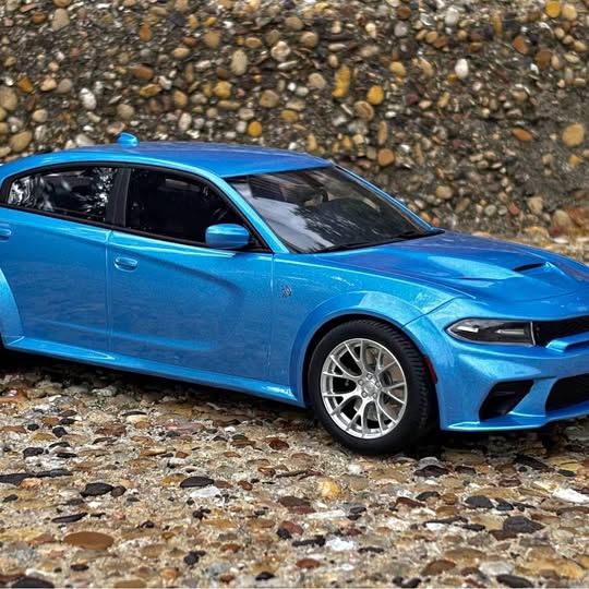 Blue 1/18 diecast muscle car model with black grille, headlights, and silver wheels